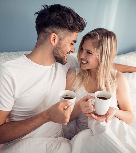 Paar mit Kaffee im Hotelbett