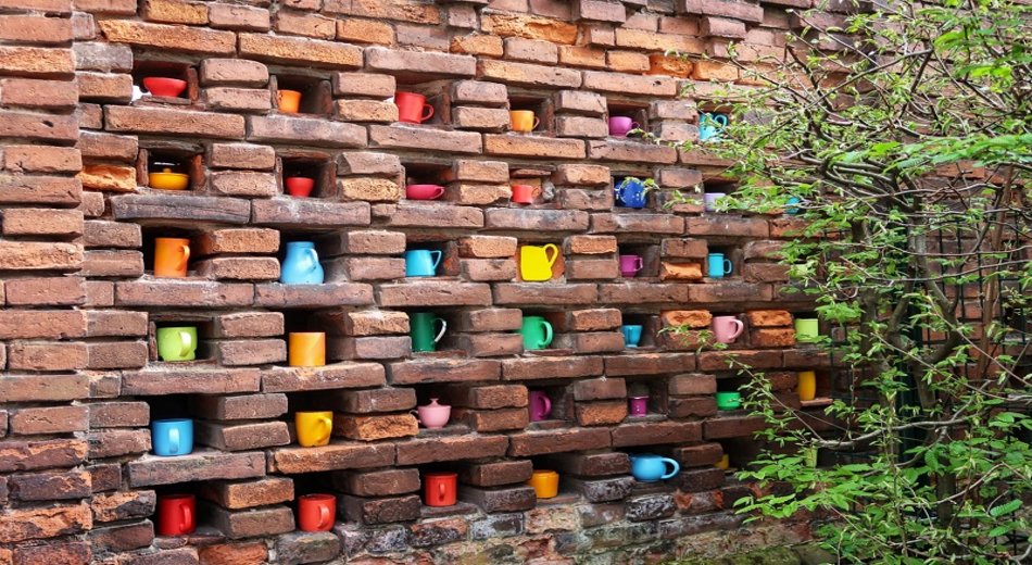 Tassen, die integriert in eine alte Backsteinmauer wie ein Kunstwerk erscheint