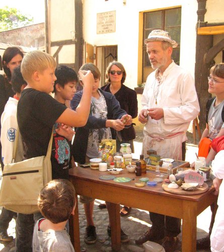 Gruppe an Personen stehen um einen Tisch und begutachten Gläser bei der Farbenküche